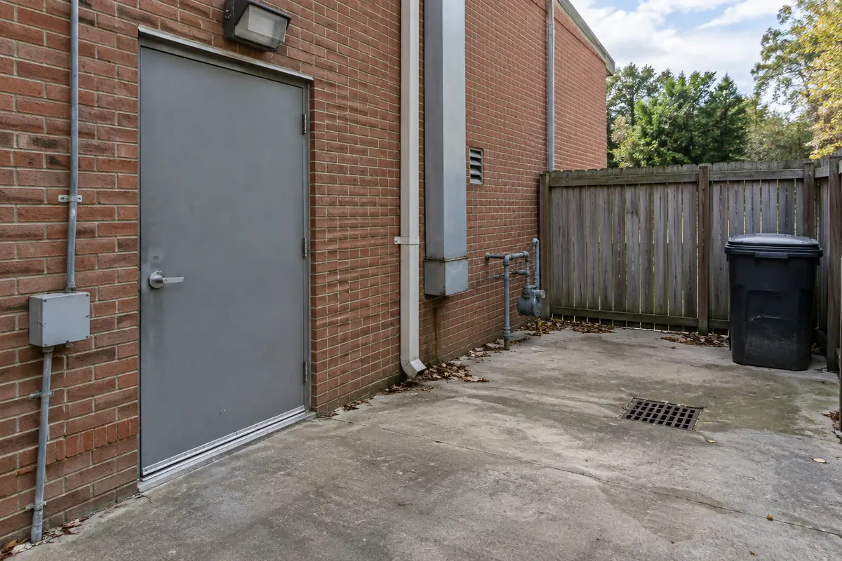 Brick building with a gray rear door, a trash bin and a floor drain, commercial pest control in Menifee, CA